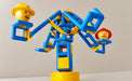 Toy figure on a blue and yellow seesaw with a plain background