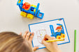 Child coloring a picture of a toy construction vehicle with a coloring book and crayon.